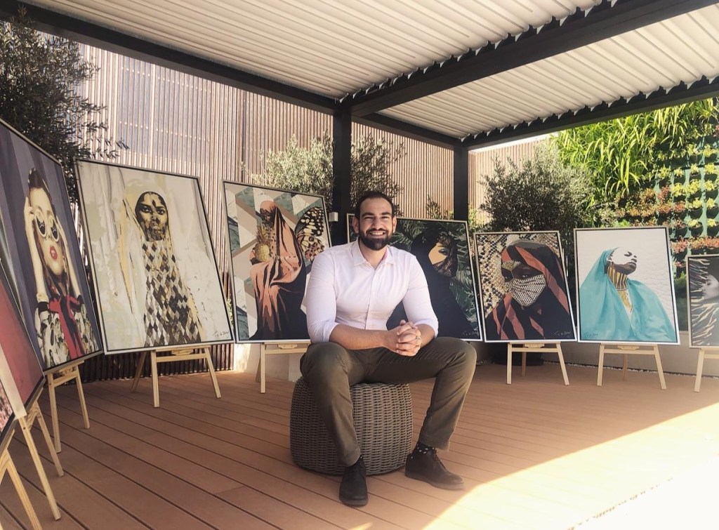 image of artist Tarek Shafagoj sitting in front of his painting collection Women of the East